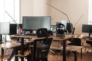Büro Arbeitsplätze mit vielen Tischen, Stühlen und Bildschirmen.